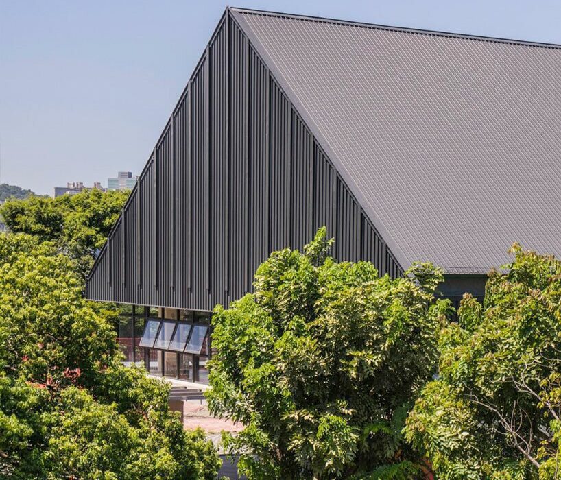 triangular metal roof crowns elevated sports hall in taiwan school extension