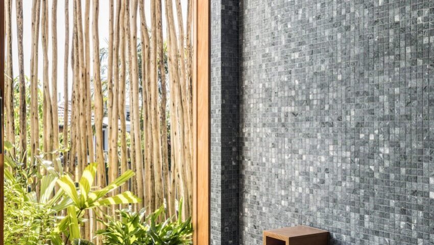 Bathroom with sunken bath, blue tiled walls and a window overlooking a garden
