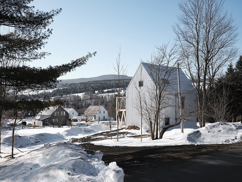 white cladding envelops la musette gabled village hut in canada